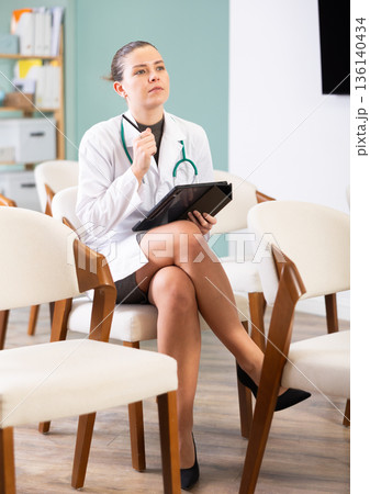 During lecture, young woman medical listener makes notes on tablet 136140434