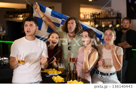 Group of friends cheer together for their favorite Greek team in beer bar Group of friends cheer together for their favorite Greek team in beer bar 136140443