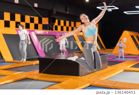 Young woman trains jumping in trampoline center Young woman trains jumping in trampoline center 136140451