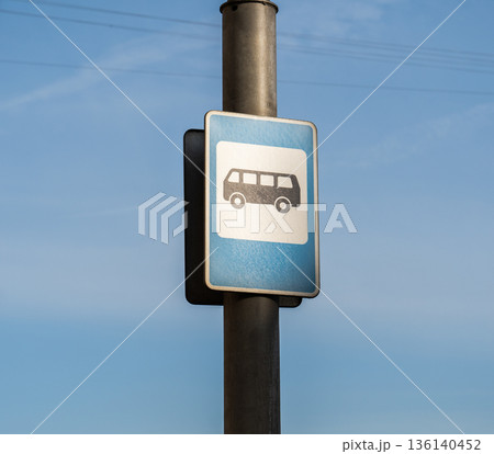 Bus stop sign signaling public transportation availability under clear blue sky 136140452