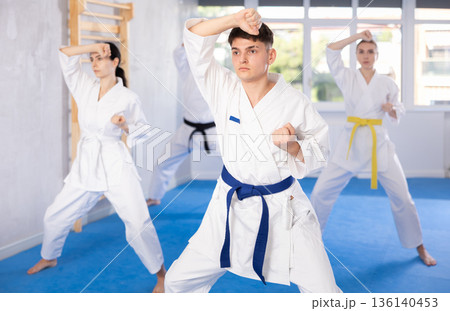Fighting stance of men and women during group karate training in gym Fighting stance of men and women during group karate training in gym 136140453