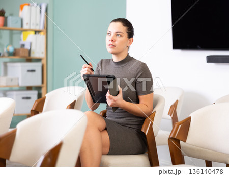 Young woman student taking notes on tablet in lecture hall 136140478