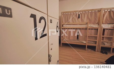 Hostel dormitory with bunk beds offering privacy curtains and personal lockers for travelers Hostel dormitory with bunk beds offering privacy curtains and personal lockers for travelers 136140481