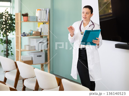 Girl doctor speaker with paper data report during lecture 136140523