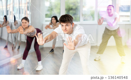 Happy young man and group of international dancers training before big performance in dance class Happy young man and group of international dancers training before big performance in dance class 136140548
