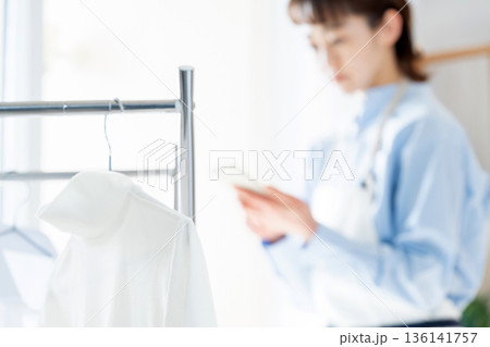 家事をしながらスマホを見る若い女性 136141757