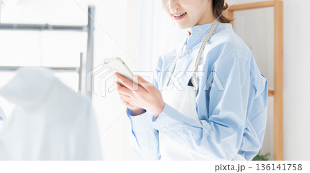 家事をしながらスマホを見る若い女性 家事をしながらスマホを見る若い女性 136141758