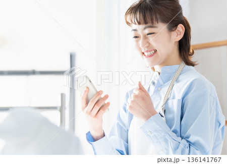 家事をしながらスマホを見る若い女性 家事をしながらスマホを見る若い女性 136141767