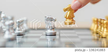 hand moving gold Chess knight figure and Checkmate opponent during chessboard competition. Strategy, Success, management, business planning, win, disruption, Trade war and leadership concept 136141863