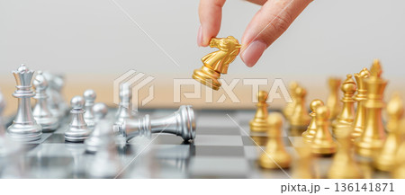 hand moving gold Chess knight figure and Checkmate opponent during chessboard competition. Strategy, Success, management, business planning, win, disruption, Trade war and leadership concept 136141871
