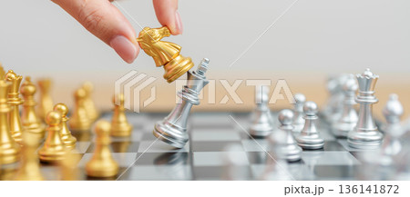 hand moving gold Chess King figure and Checkmate opponent during chessboard competition. Strategy, Success, management, business planning, win, disruption, Trade war and leadership concept 136141872