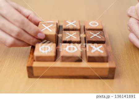 Hand holding and playing wooden block of tic tac toe game. A completed game of noughts and crosses or Xs and Os game. Challenge, Competition, winning, tactic, strategy and recreation concepts Hand holding and playing wooden block of tic tac toe game. A completed game of noughts and crosses or Xs and Os game. Challenge, Competition, winning, tactic, strategy and recreation concepts 136141891