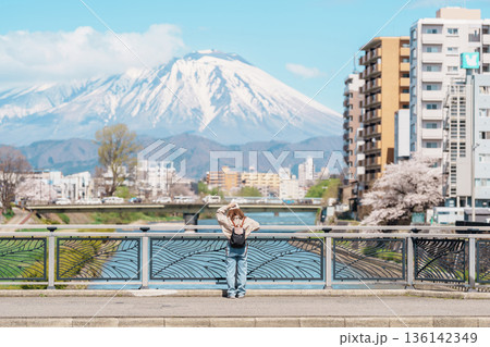 Woman tourist sightseeing Iwate mountain and Kitakami river with flowers in Spring, happy traveler travel in Morioka city, Iwate prefecture, Japan. famous Landmark Travel and Vacation destination Woman tourist sightseeing Iwate mountain and Kitakami river with flowers in Spring, happy traveler travel in Morioka city, Iwate prefecture, Japan. famous Landmark Travel and Vacation destination 136142349