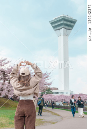 Woman tourist sightseeing Goryokaku Tower park with Sakura Cherry Blossom in Spring, happy traveler travel in Hakodate city, Hokkaido, Japan. famous Landmark, Japan Travel and Vacation destination 136142372