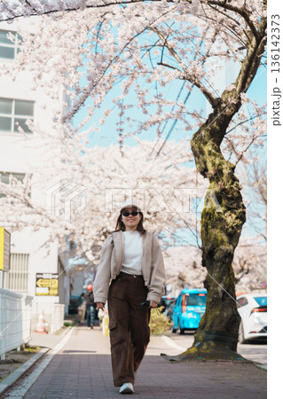 Woman tourist sightseeing Goryokaku Tower park with Sakura Cherry Blossom in Spring, happy traveler travel in Hakodate city, Hokkaido, Japan. famous Landmark, Japan Travel and Vacation destination 136142373