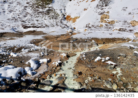 「登別地獄谷」茶色い土と雪の中を湧き出した温泉が川のように流れる 136142435