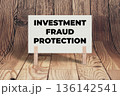 Concept words Investment Fraud Protection, White Concrete Texture Rectangle Card Held By Clothespin Wooden Texture Background, Business and Investment Fraud Protection Theme 136142541