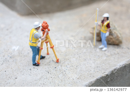 Miniature Surveyors Working With Tripod Equipment On Concrete Surface 136142977