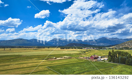 Aerial Wyoming Farmland Red Barn and Mountain Range Under Vibrant Sky Aerial Wyoming Farmland Red Barn and Mountain Range Under Vibrant Sky 136143292