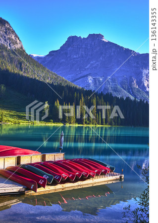 Emerald Lake Canoes on Dock with Reflections and Majestic Mountain Backdrop 136143355