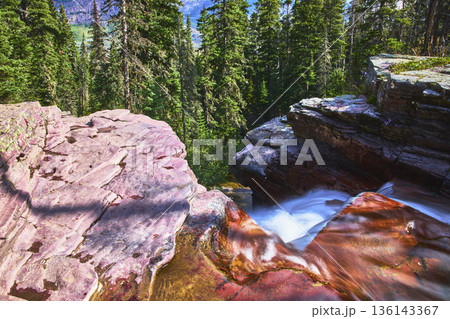 Waterfall and Red Rock Ledges with Evergreen Forest in Sunlight 136143367