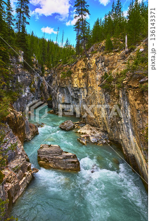 Turquoise River Flowing Through Steep Canyon Cliffs and Forested Landscape Turquoise River Flowing Through Steep Canyon Cliffs and Forested Landscape 136143371
