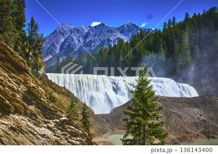 Waterfall Rushing Water and Pine Trees with Majestic Mountain Backdrop 136143400