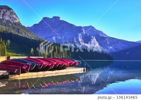 Canoes and Wooden Dock on Pristine Mountain Lake with Dramatic Alpine Peaks Reflected Canoes and Wooden Dock on Pristine Mountain Lake with Dramatic Alpine Peaks Reflected 136143465