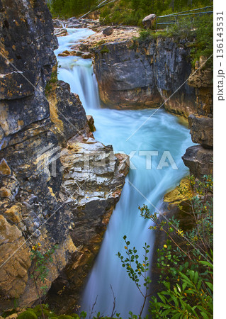 Waterfall Flowing Through Rocky Canyon with Turquoise River and Lush Greenery Waterfall Flowing Through Rocky Canyon with Turquoise River and Lush Greenery 136143531