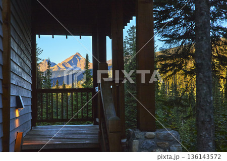 Mountain Peak Framed by Cabin Porch and Evergreen Forest in Morning Light Mountain Peak Framed by Cabin Porch and Evergreen Forest in Morning Light 136143572
