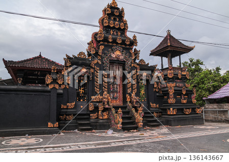 Traditional Balinese temple gate with gold ornaments under cloudy sky for travel concept 136143667