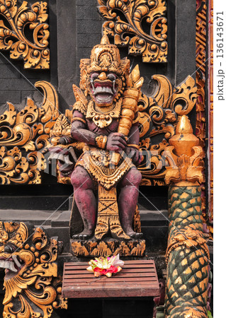 Balinese guardian statue standing at temple entrance with traditional offerings for travel concept Balinese guardian statue standing at temple entrance with traditional offerings for travel concept 136143671