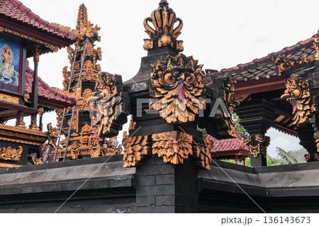 Balinese temple stone carving with gold leaf details under natural light for travel concept Balinese temple stone carving with gold leaf details under natural light for travel concept 136143673