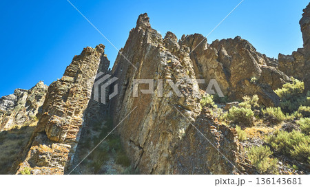 Rocky Formations and Shrubs Under Clear Blue Sky Low Perspective 136143681