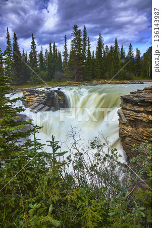 Athabasca Falls Waterfall and Lush Forest Under Dramatic Sky in Jasper National Park 136143987