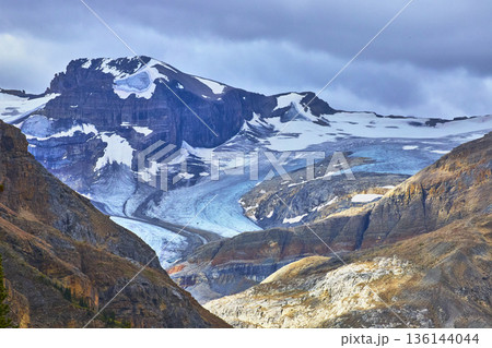 Glacier and Snow Capped Mountain with Rocky Slopes in Rugged Wilderness Landscape Glacier and Snow Capped Mountain with Rocky Slopes in Rugged Wilderness Landscape 136144044