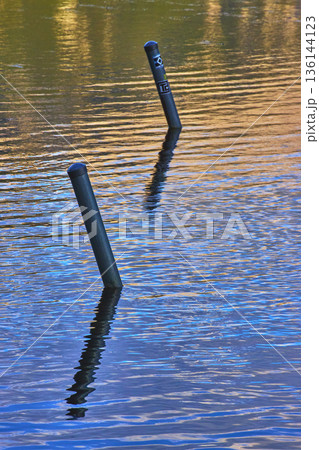 Reflections and Posts in Tranquil Blue and Gold Lake Water Reflections and Posts in Tranquil Blue and Gold Lake Water 136144123