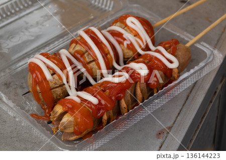Grilled meatballs and sausage skewers with chili sauce in plastic container for street food concept Grilled meatballs and sausage skewers with chili sauce in plastic container for street food concept 136144223