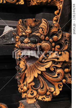 Balinese stone carving with gold leaf finish on dark temple wall for Indonesian culture concept 136144244