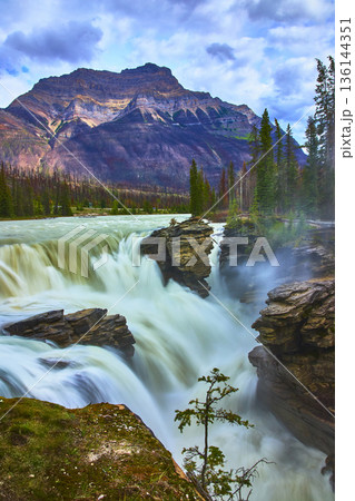 Athabasca Falls Waterfall Rushing Water and Rocky Cliffs with Mountain in Jasper Athabasca Falls Waterfall Rushing Water and Rocky Cliffs with Mountain in Jasper 136144351
