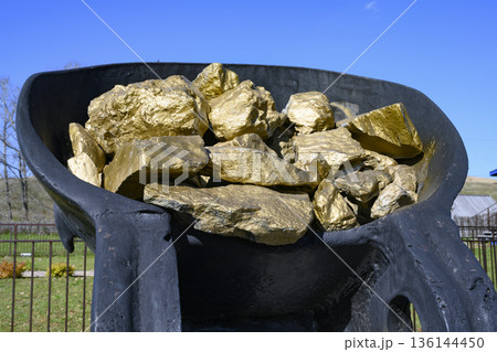 Monument to gold miners in the form of huge pieces of gold in a metal bucket Monument to gold miners in the form of huge pieces of gold in a metal bucket 136144450