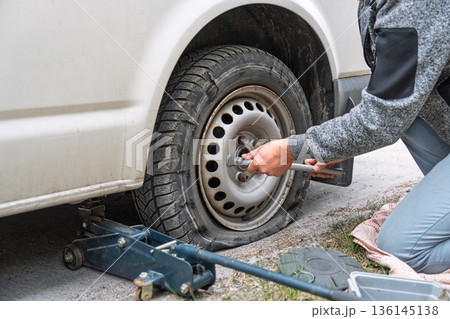 Changing a Flat Tire on a Car with a Jack in an Emergency Roadside Situation. Man Working 136145138