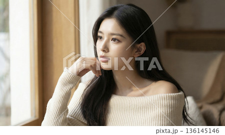 窓辺でオフショルダーのニットを着て外を眺める美しい日本人女性 136145146