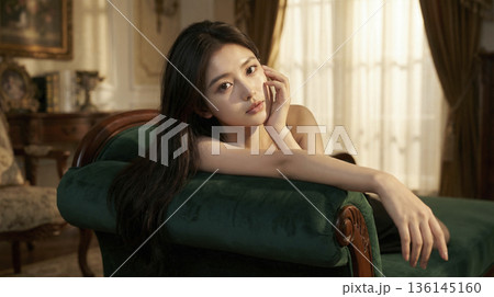 緑のソファに寄りかかり黒いドレスを着て寛ぐラグジュアリーな女性 136145160