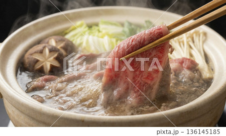 土鍋の中でぐつぐつと煮える牛肉と野菜の鍋料理のクローズアップ 136145185