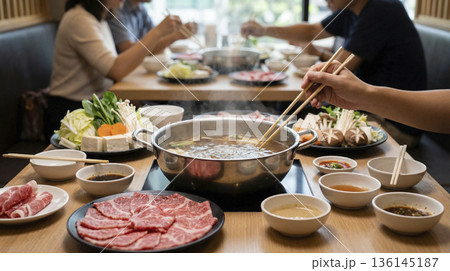 レストランで鍋を囲んでしゃぶしゃぶを楽しむグループの食事風景 136145187