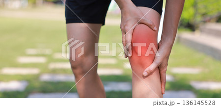 Close-up of woman hand holding painful injured knee with red inflamed spot and bruising. Medical concept of joint pain, arthritis, bone injury, muscle ache, or sprain in outdoor sunlight background. Close-up of woman hand holding painful injured knee with red inflamed spot and bruising. Medical concept of joint pain, arthritis, bone injury, muscle ache, or sprain in outdoor sunlight background. 136145528