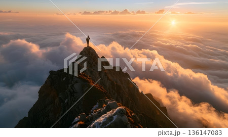 雲海を見下ろす山頂に立つ小さな人影と感動の朝焼け風景 136147083