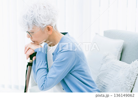 リビングで杖を手に落ち込むシニア女性 リビングで杖を手に落ち込むシニア女性 136149062