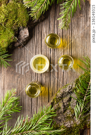 Essential fir oil bottles surrounded by pikhta branches and moss on olwooden surface Essential fir oil bottles surrounded by pikhta branches and moss on olwooden surface 136149315
